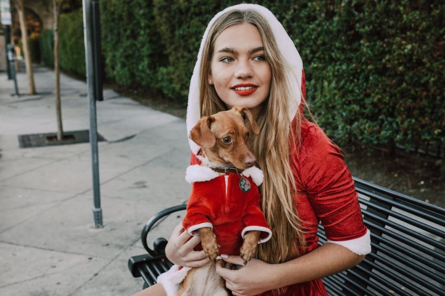 a woman and her dog in Christmas costumes sitting on a bench